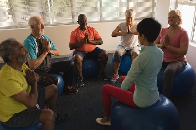 Photo female trainer training senior people in performing yoga