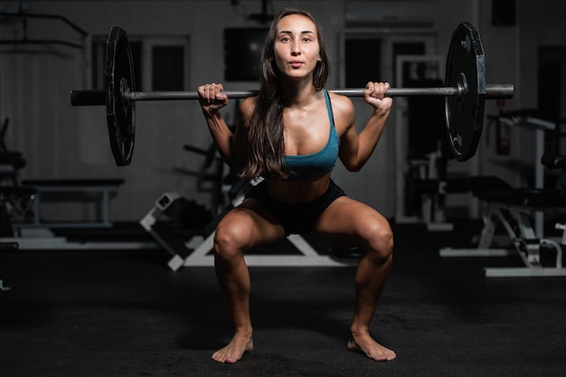 Female training with barbell, pumping legs