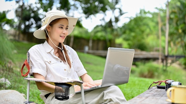 Blogger di viaggio femminile che lavora a distanza utilizzando il laptop durante una vacanza in campeggio