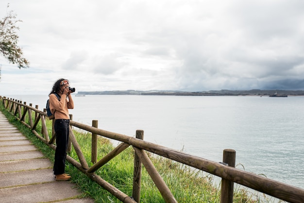 female traveler in casual clothes taking photo of rippling sea