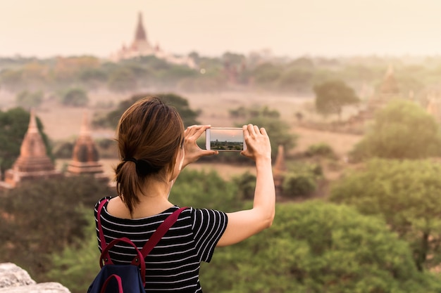 Женский путешественник фотографирует древнюю пагоду в Багане