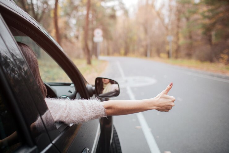 Photo 親指を立てて道路上の女性旅行者。秋の休暇、休日、旅行、ロードトリップ、人々のコンセプト。手を閉じます。秋のコンセプト。車での秋の森の旅。
