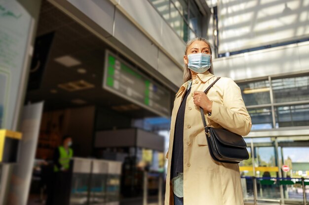 전염병 동안 비행기를 기다리는 동안 의료 안전 마스크를 쓴 여성 여행자