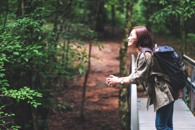 Foto un viaggiatore femminile con uno zaino che cammina nel bosco