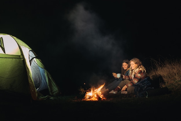 Female travelers sitting near bonfire