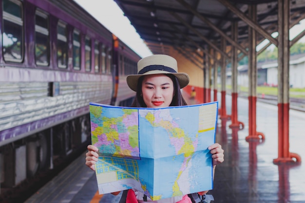 Foto viaggiatori femminili che portano uno zaino che porta una mappa per il viaggio in treno.