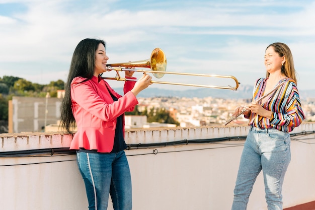 Photo female trombonist and flutist laughing at a rehearsal