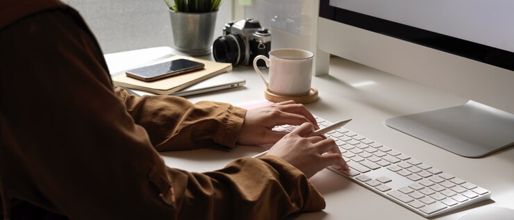 Photo female typing on computer keyboard on white office desk with smartphone and office supplies