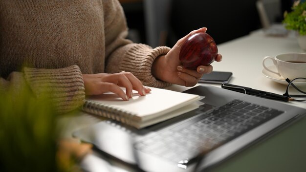 A female university student eating apple while studying math on online class at home Remote work