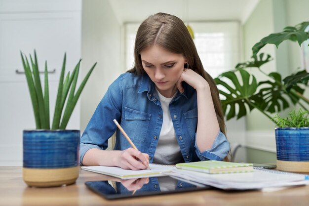 Female university student studies at home writes in a notebook