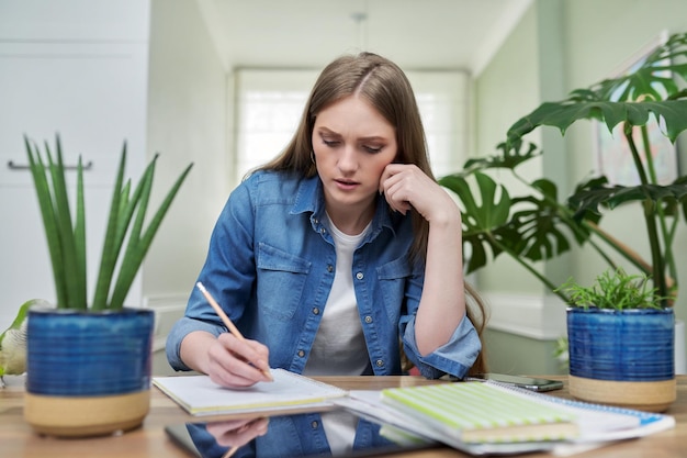 Foto la studentessa universitaria femminile studia a casa scrive su un taccuino