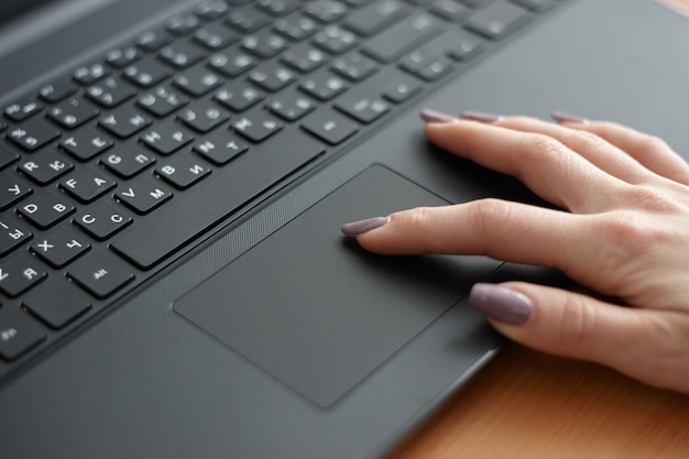 仕事のために黒いラップトップを使用している女性。タッチパッドを使用してインターネットサーフィン。ビジネスコンセプト