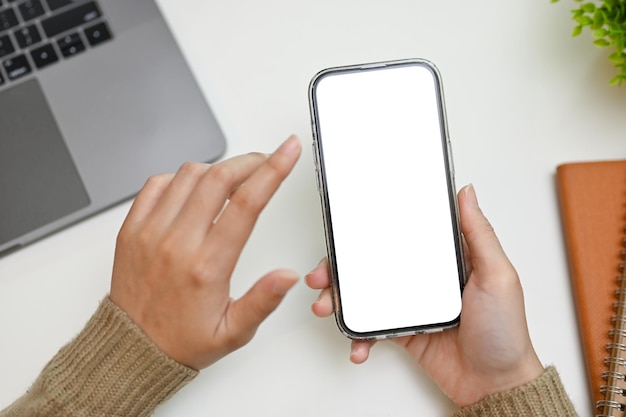 A female using her smart mobile phone over her office desk phone white screen mockup