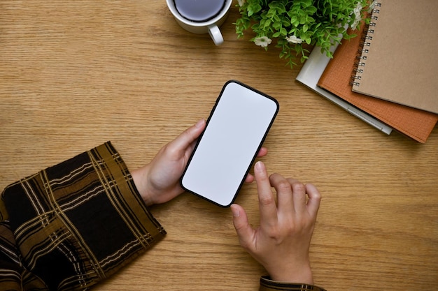 A female using her smartphone at her desk smartphone white screen mockup top view