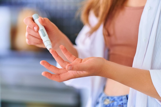 Femmina che usa la lancetta sul dito per misurare e controllare il livello di glucosio nel sangue trattamento del diabete mellito e sanitario