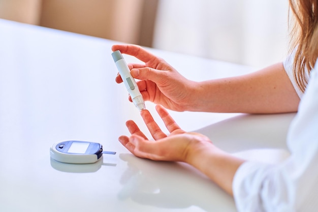 사진 혈당 수치를 측정하고 확인하기 위해 손가락에 랜서를 사용하는 여성 건강 및 진성 당뇨병 치료