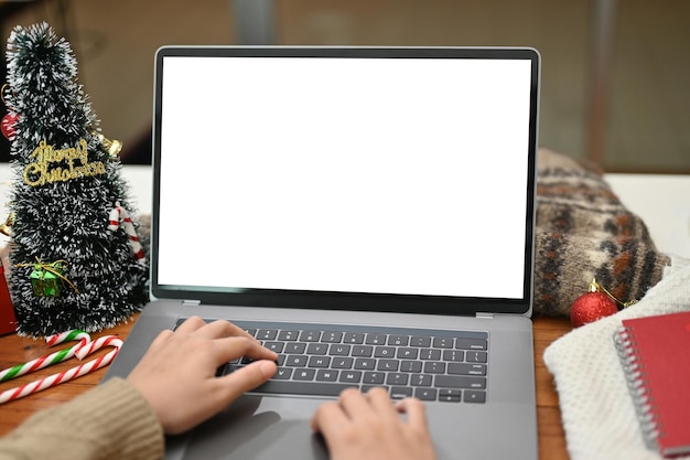 A female using laptop typing on keyboard working at her desk with Christmas decor on table