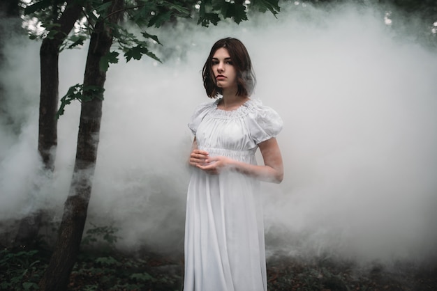 Female victim in white dress in the misty forest