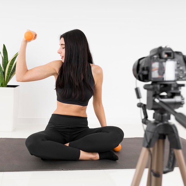 Female vlogger at home with weights exercising