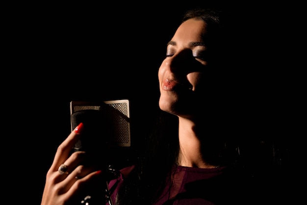 Female vocal artist singing in a recording studio.