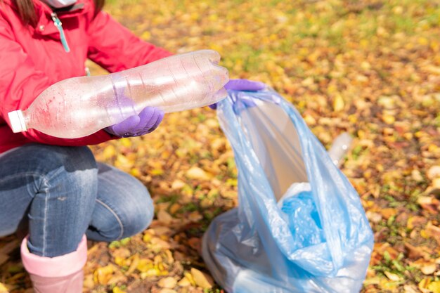 A female volunteer cleans plastic garbage in nature.