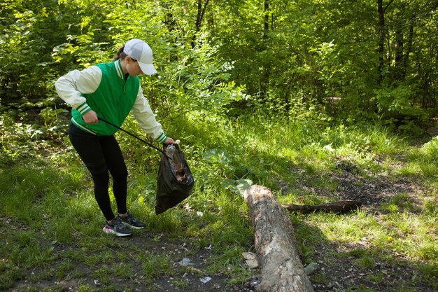 Female volunteer collecting waste and rubbish in the forest, copy space