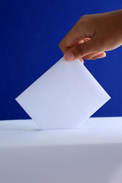 Photo female voter put vote card to ballot box