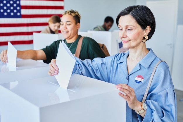 Photo female voters putting ballots in bin