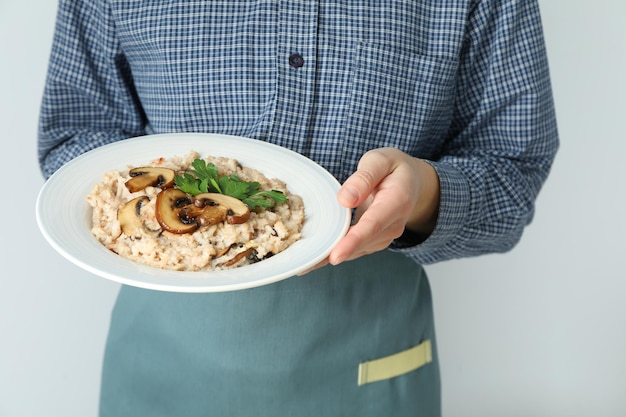 Female waiter holding a plate of risotto with mushrooms