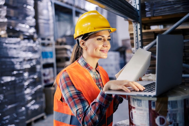 Photo a female warehouse worker adding box on order list on laptop