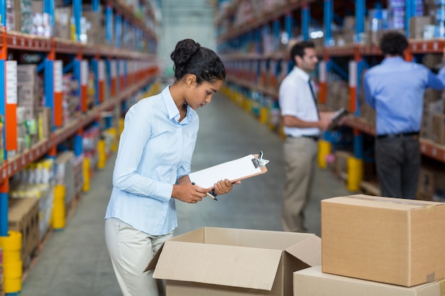 Photo female warehouse worker with a clipboard checking the boxes