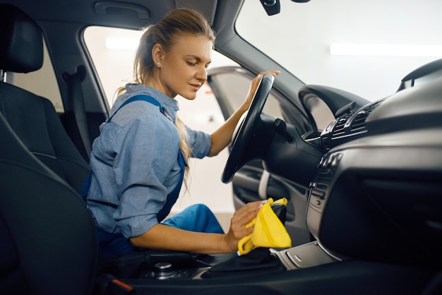 Female washer with sponge cleans automobile door trim, car wash\
service. woman washes vehicle, carwash station, car-wash\
business