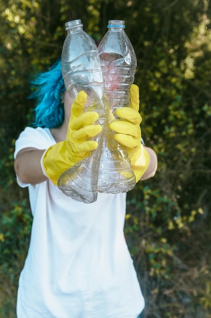 Female wearing gloves holding recyclable plastic bottles - plastic pollution concept