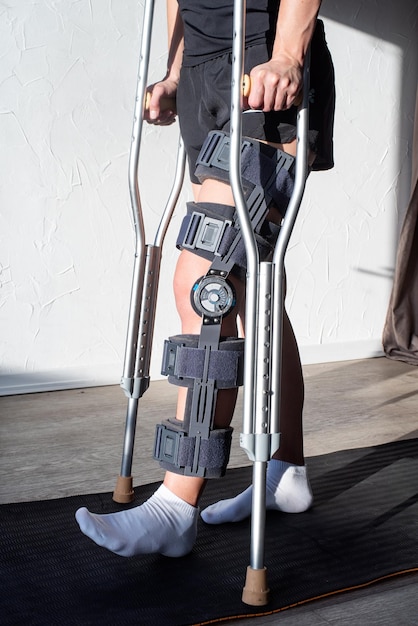 Female wearing knee orthosis or knee support brace after surgery on leg