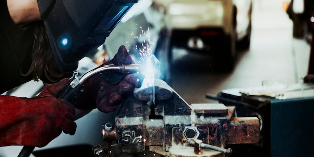 Female welding a metal piece in the garage