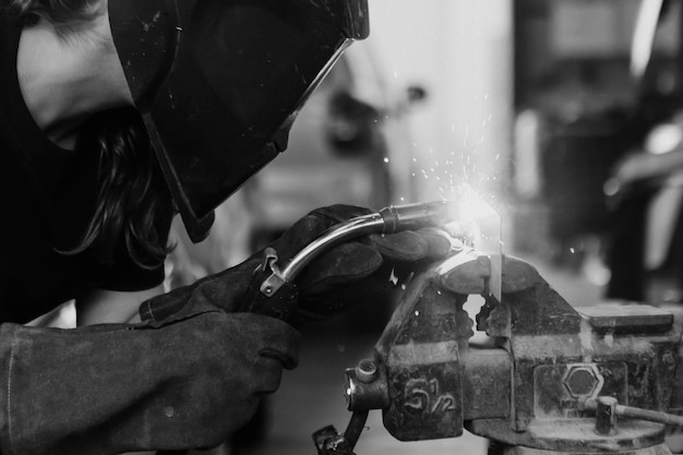 Female welding a metal piece in the garage