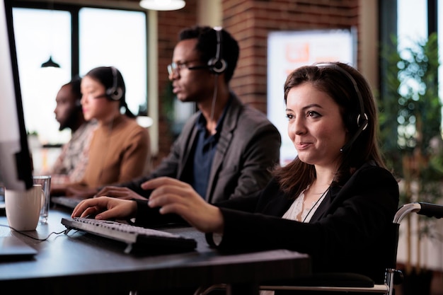 Photo female wheelchair user with impairment working at call center reception, helping clients at cutomer care service. woman living with physical disability giving telemarketing support and assistance.