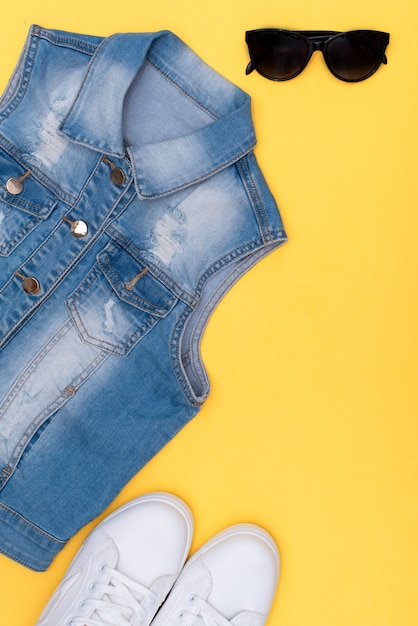 Female white sneakers and jeans on yellow background with copy space. 