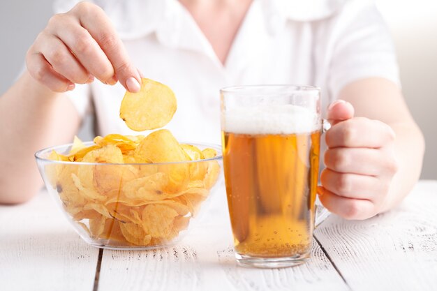 Female with heap of potato chips in big dish