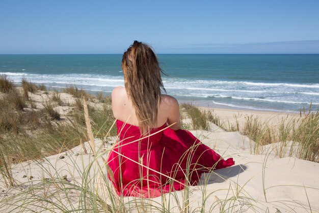 Female with a red dress admiring a marine view