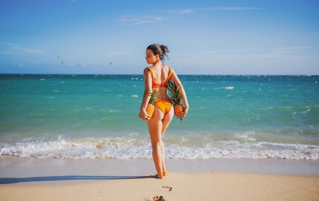 Female with sexy buttocks in swimsuit young woman holding a pineapple hot summer holiday on jamaica