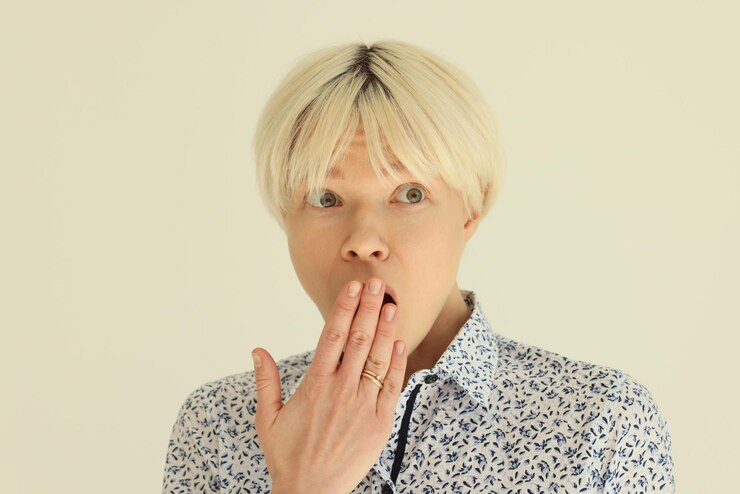 Photo 짧은 공정한 머리를 가진 여성은 놀랍게도 놀란 젊은 여성의 반응으로 손바닥으로 입을 덮습니다.