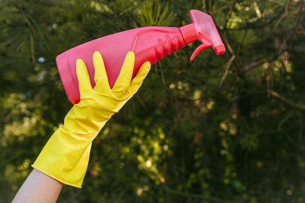 Female with yellow gloves holding a plastic cleaning spray bottle - plastic pollution concept