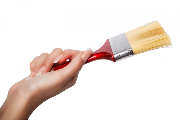 Foto una mano femminile (donna) in possesso di un pennello rosso isolato bianco, vista dall'alto in studio.