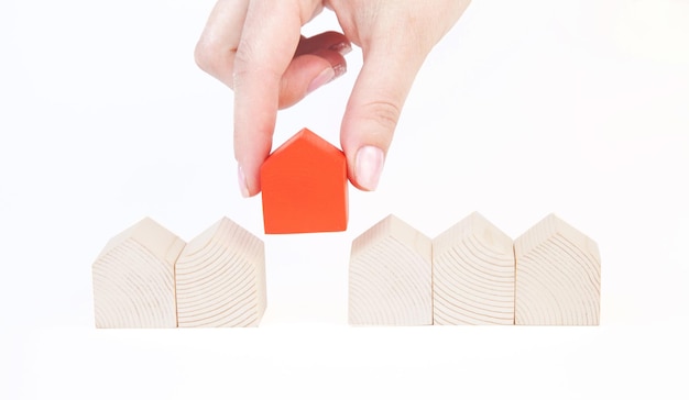 A female(woman) hand pick up a wood house isolated white background