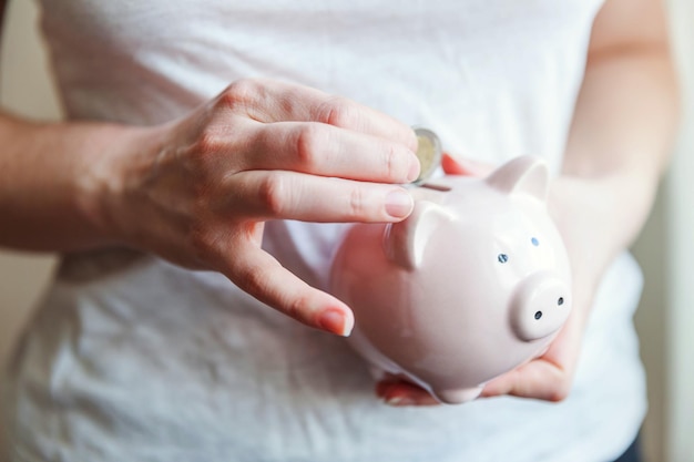 Female woman hands holding pink piggy bank and putting money Euro coin Saving investment budget business wealth retirement financial money banking concept