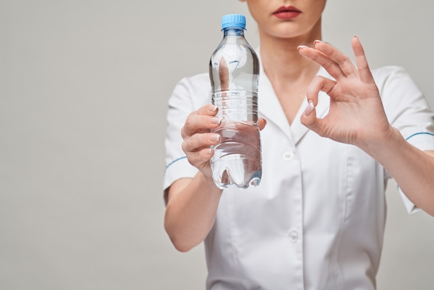 女性女性栄養士または栄養士医師の健康的なライフスタイルの概念-水のボトルを保持します