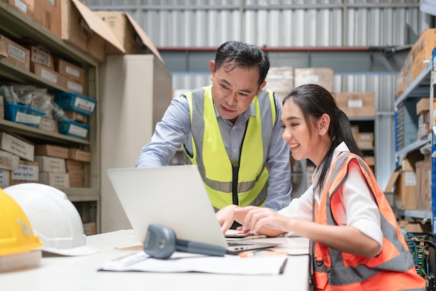 Female worker discussing with senior male manager use laptop checking products in stock at warehouse