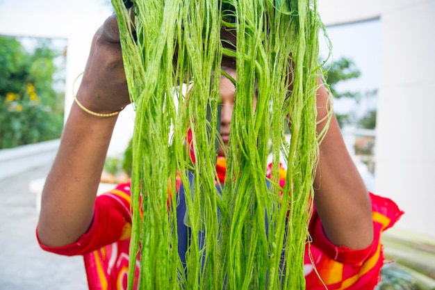 未洗浄のパイナップルの葉の緑の繊維を展示する女性労働者 環境に優しいパイナップルの葉の繊維 農業廃棄物
