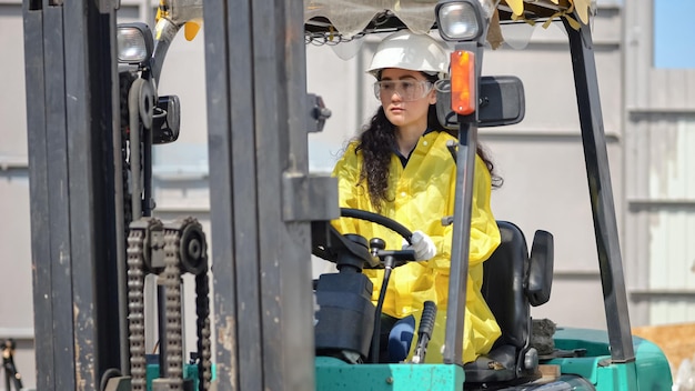 Photo female worker in hardhat drives loader among piles of unsorted trash in waste sorting plant yard blackhaired woman works at trash processing factory